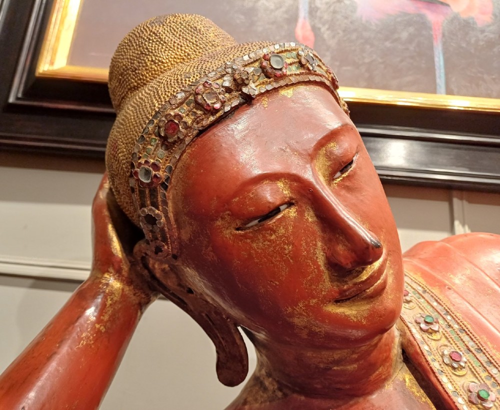 A 19th-century Burmese carved wooden sculpture of a reclining Buddha featuring red lacquered finish and detailed gilded robes. View II