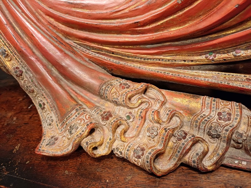 A 19th-century Burmese carved wooden sculpture of a reclining Buddha featuring red lacquered finish and detailed gilded robes. View III