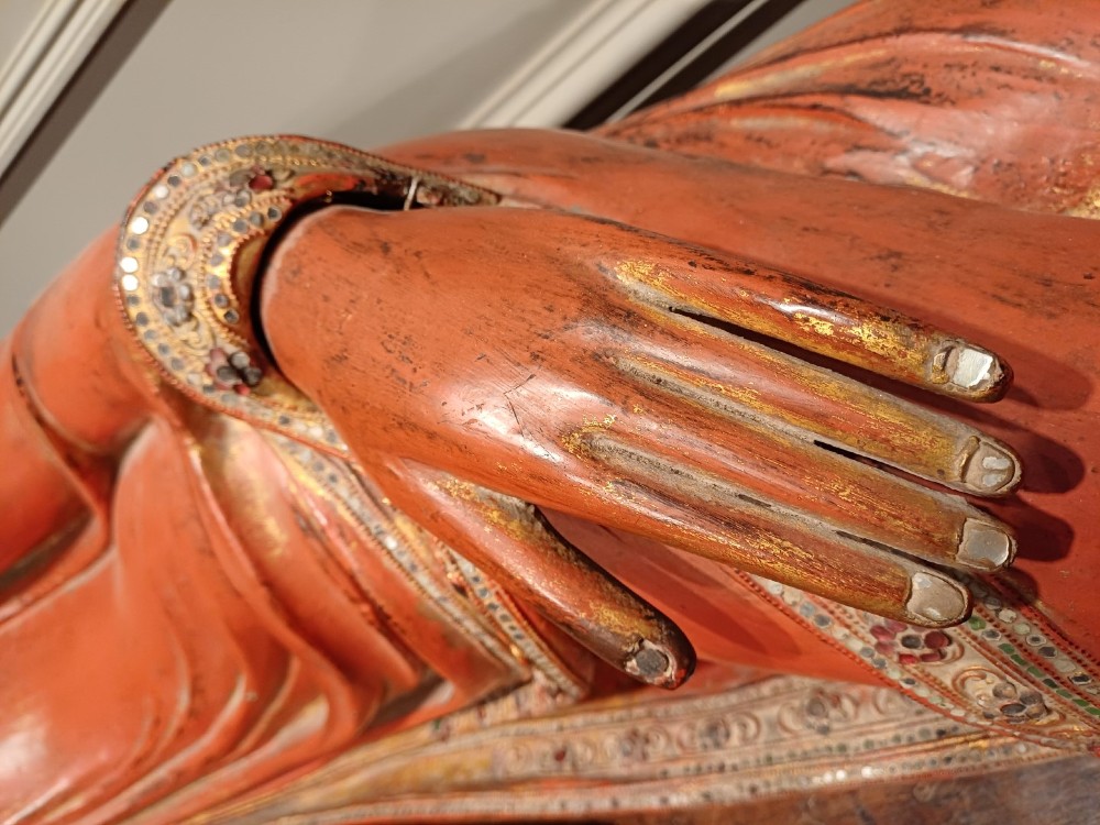 A 19th-century Burmese carved wooden sculpture of a reclining Buddha featuring red lacquered finish and detailed gilded robes. View IV
