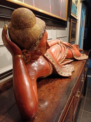 A 19th-century Burmese carved wooden sculpture of a reclining Buddha featuring red lacquered finish and detailed gilded robes. View VIII
