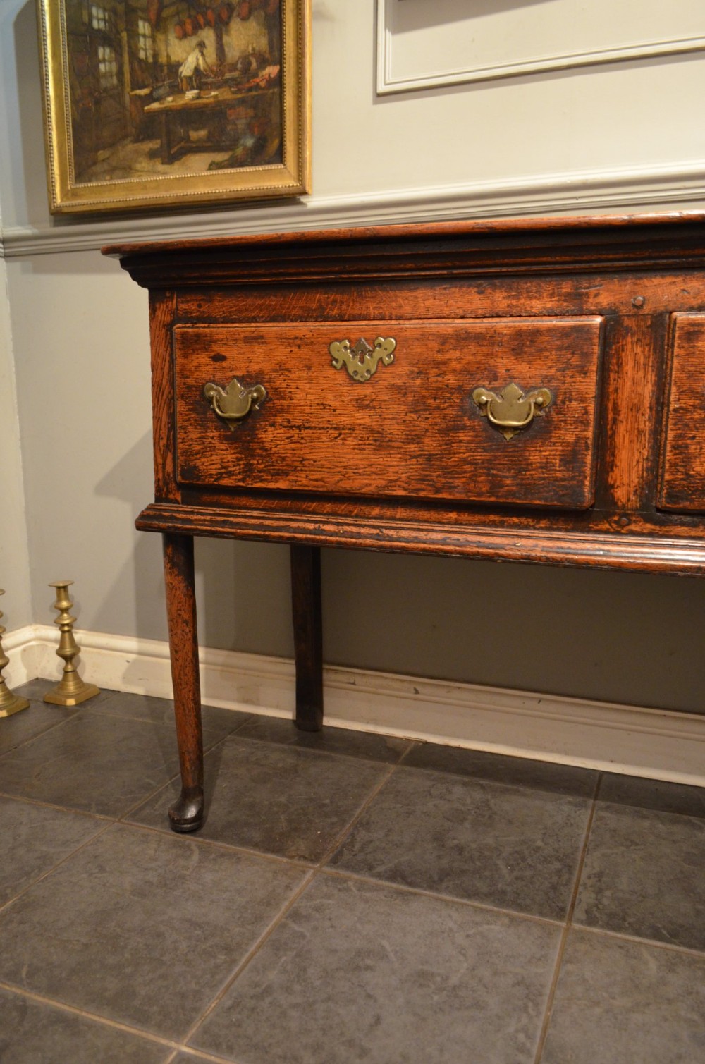 An 18th-century George III oak dresser base featuring three drawers with decorative brass handles and supported on slender legs with pad feet. View II