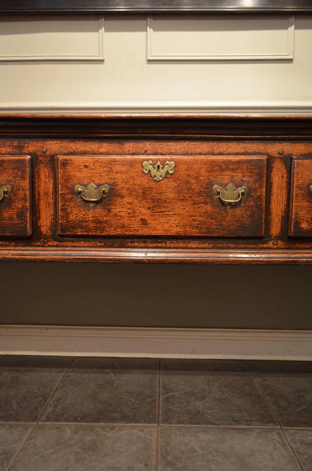 An 18th-century George III oak dresser base featuring three drawers with decorative brass handles and supported on slender legs with pad feet. View III