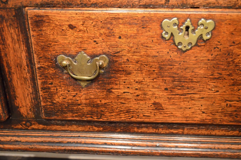 An 18th-century George III oak dresser base featuring three drawers with decorative brass handles and supported on slender legs with pad feet. View V