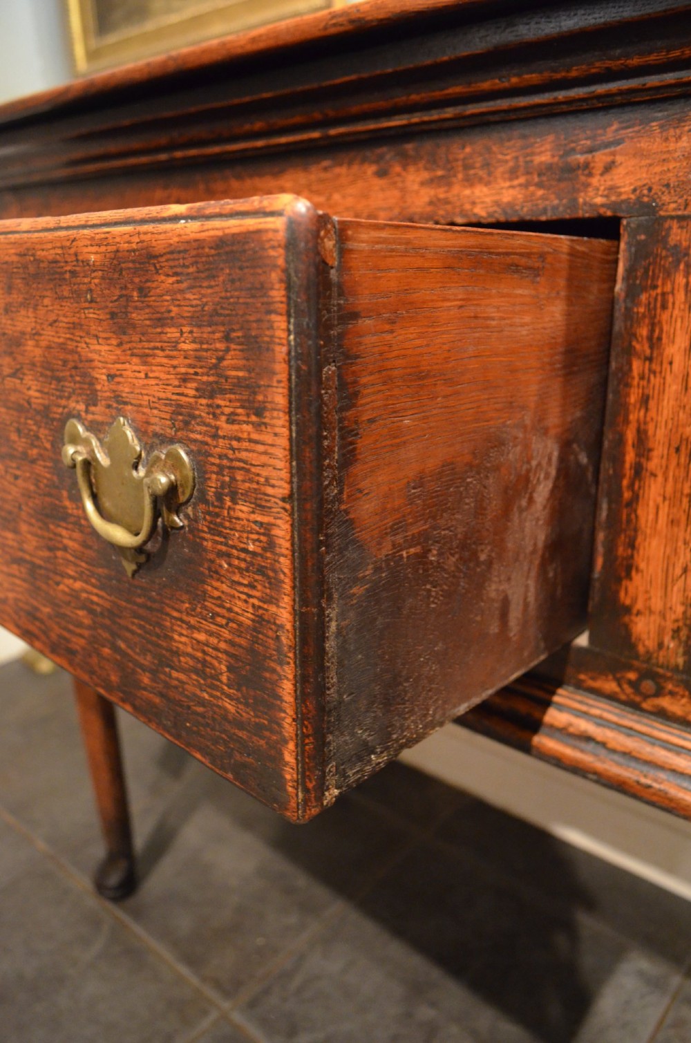 An 18th-century George III oak dresser base featuring three drawers with decorative brass handles and supported on slender legs with pad feet. View VII