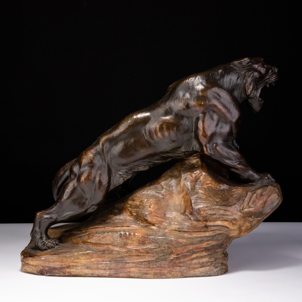 A dark brown patinated ceramic sculpture depicting a roaring tiger poised on a rocky base in the Art Deco style. View III