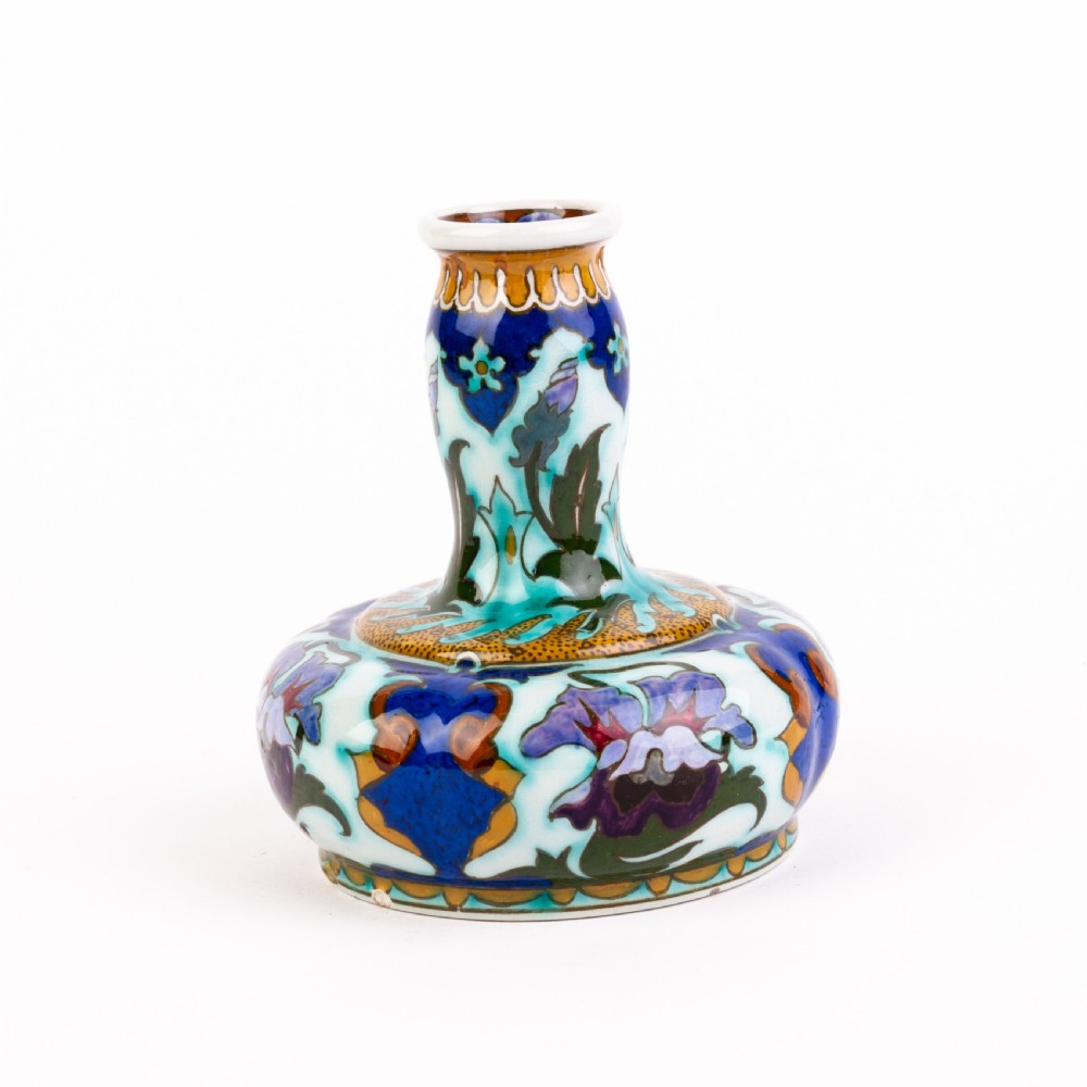 A squat, bulbous ceramic vase featuring an elongated neck, painted with polychrome Art Nouveau floral patterns in shades of blue, turquoise, orange, and purple against a white glaze. View II