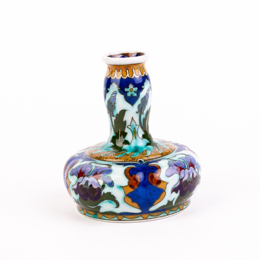 A squat, bulbous ceramic vase featuring an elongated neck, painted with polychrome Art Nouveau floral patterns in shades of blue, turquoise, orange, and purple against a white glaze. View III