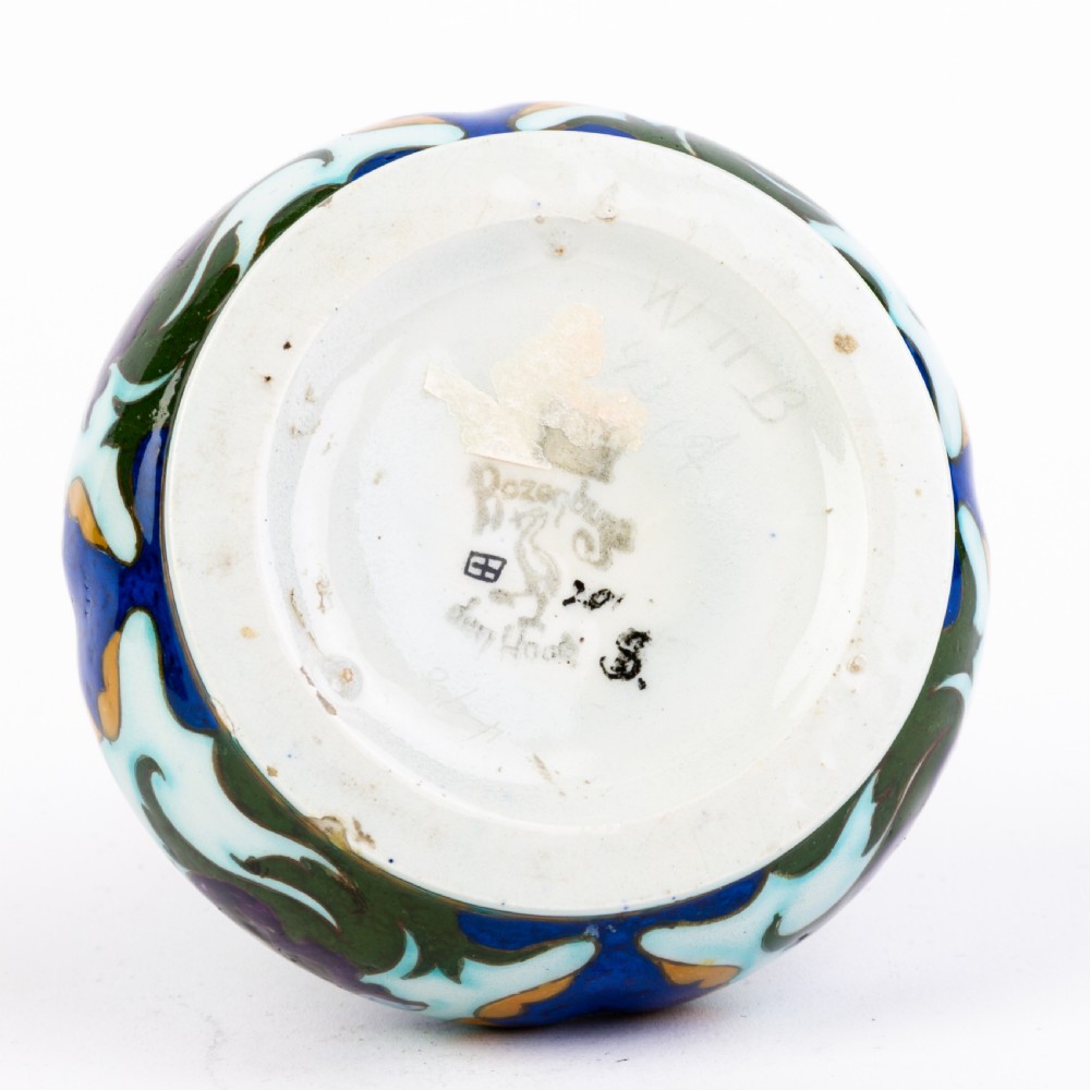 A squat, bulbous ceramic vase featuring an elongated neck, painted with polychrome Art Nouveau floral patterns in shades of blue, turquoise, orange, and purple against a white glaze. View VI