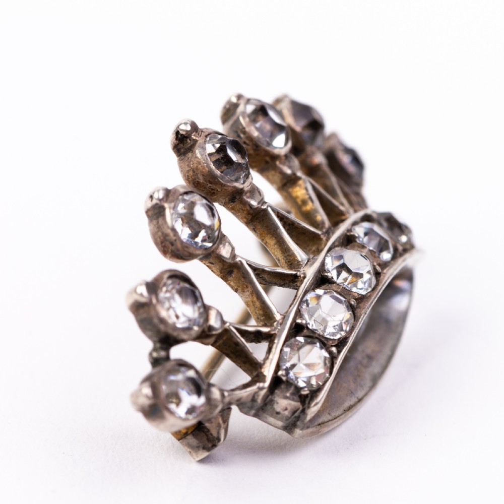 A Victorian silver brooch designed in the shape of a crown and set with round clear paste stones along the band and points. View II