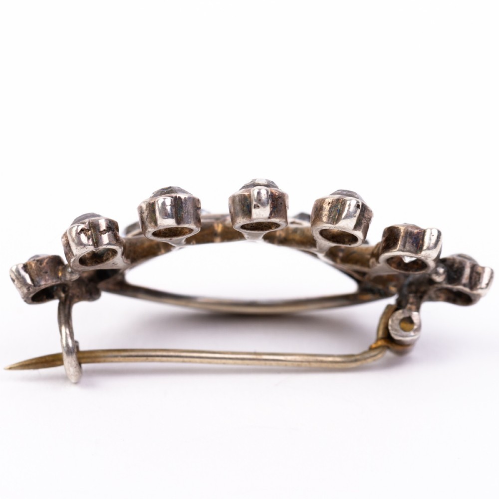 A Victorian silver brooch designed in the shape of a crown and set with round clear paste stones along the band and points. View IV
