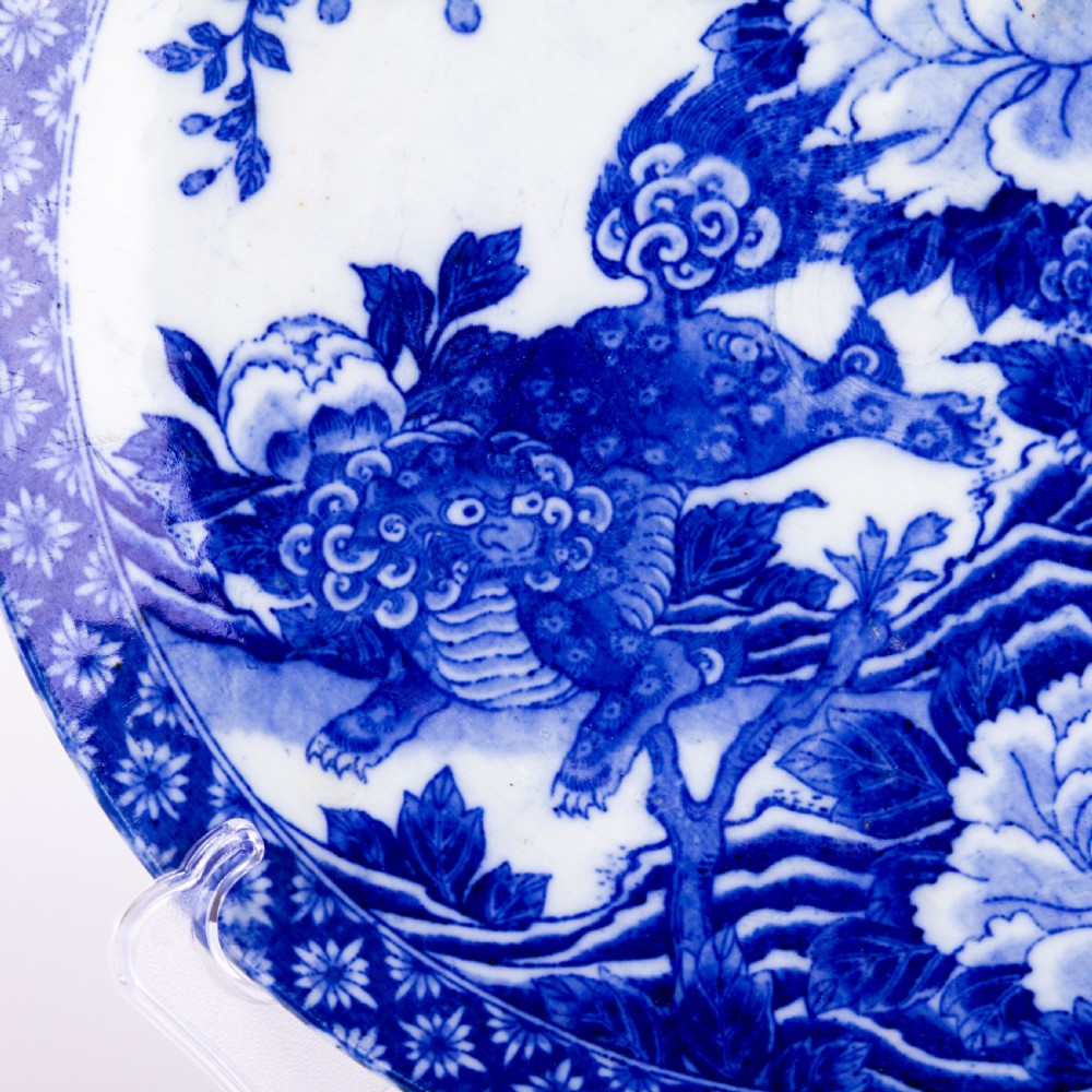 A circular blue and white Chinese porcelain display plate painted with Foo dogs and peony flowers encircled by a decorative patterned border. View III