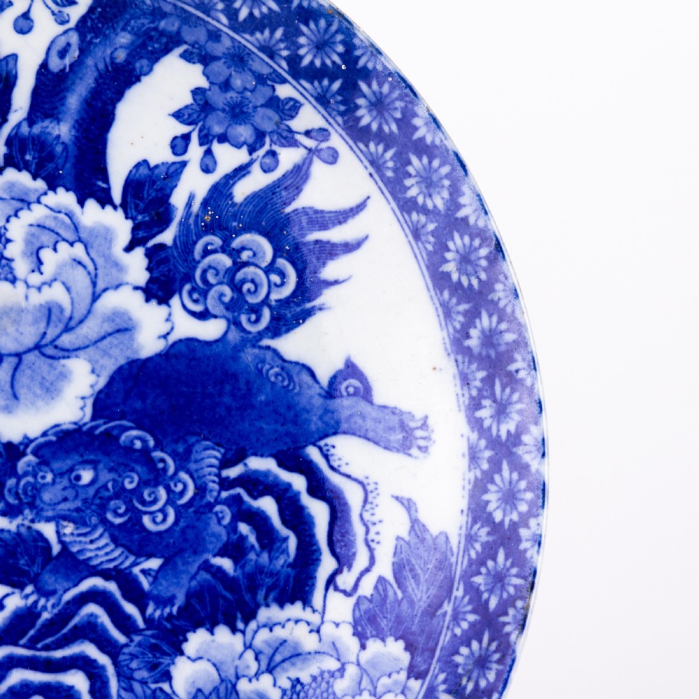 A circular blue and white Chinese porcelain display plate painted with Foo dogs and peony flowers encircled by a decorative patterned border. View V