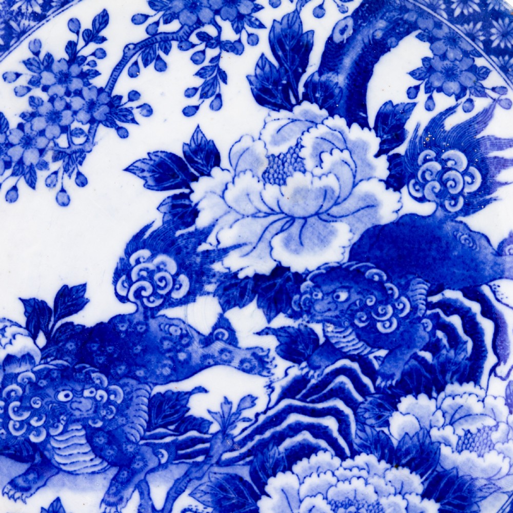 A circular blue and white Chinese porcelain display plate painted with Foo dogs and peony flowers encircled by a decorative patterned border. View VI