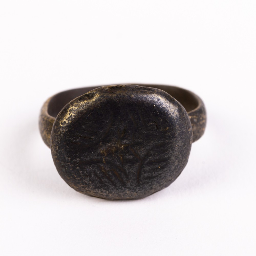 A dark patinated bronze signet ring featuring a rounded bezel hand-engraved with an eight-pointed star motif on a narrow metal band. View IV