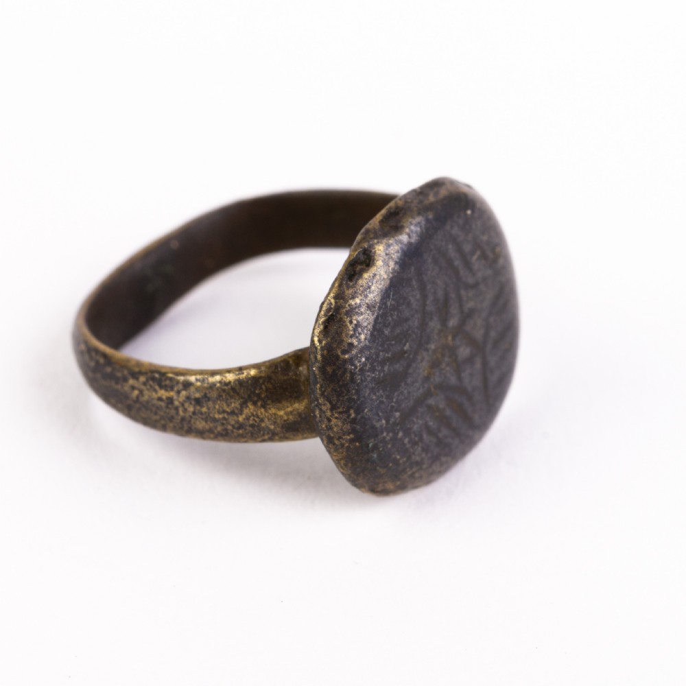 A dark patinated bronze signet ring featuring a rounded bezel hand-engraved with an eight-pointed star motif on a narrow metal band. View III