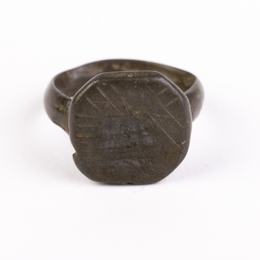 A dark patinated bronze signet ring featuring an octagonal bezel with faint geometric hand-engraved markings.