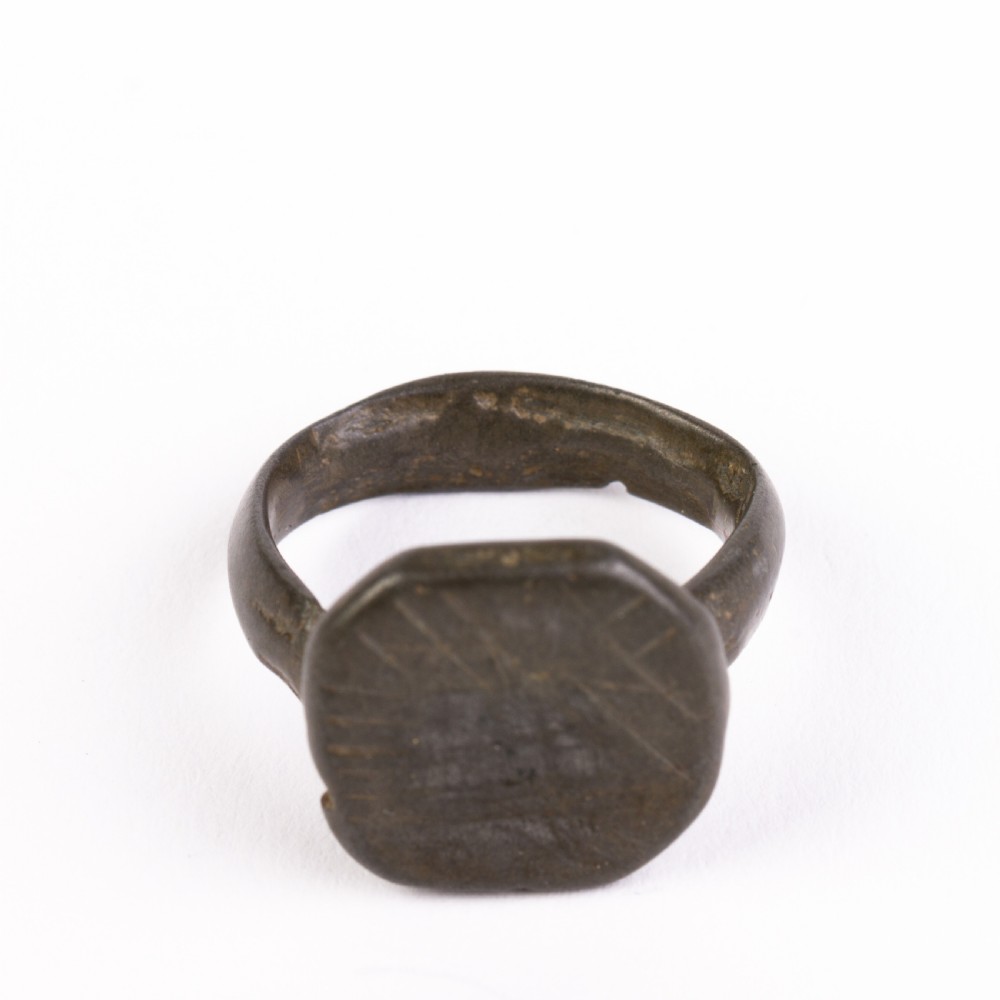 A dark patinated bronze signet ring featuring an octagonal bezel with faint geometric hand-engraved markings. View V