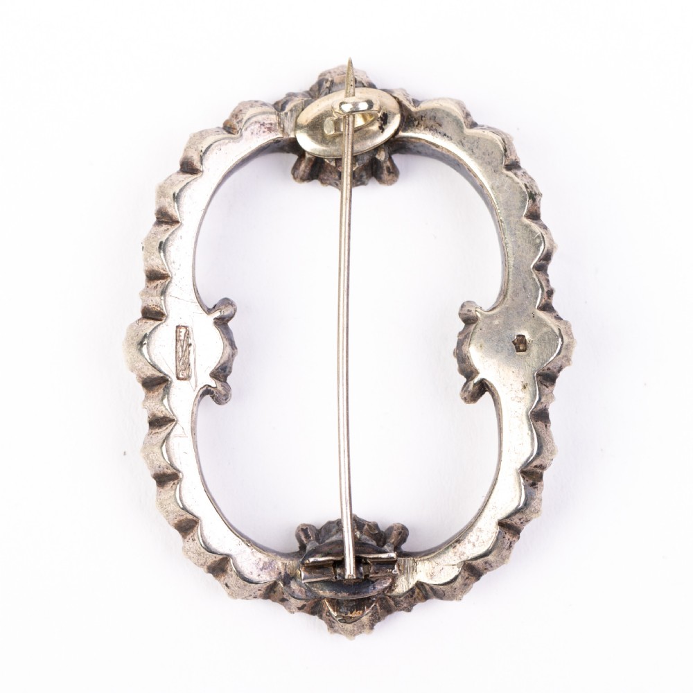 A nineteenth-century Victorian openwork oval buckle brooch set with faceted clear paste glass stones in a silver setting. View II