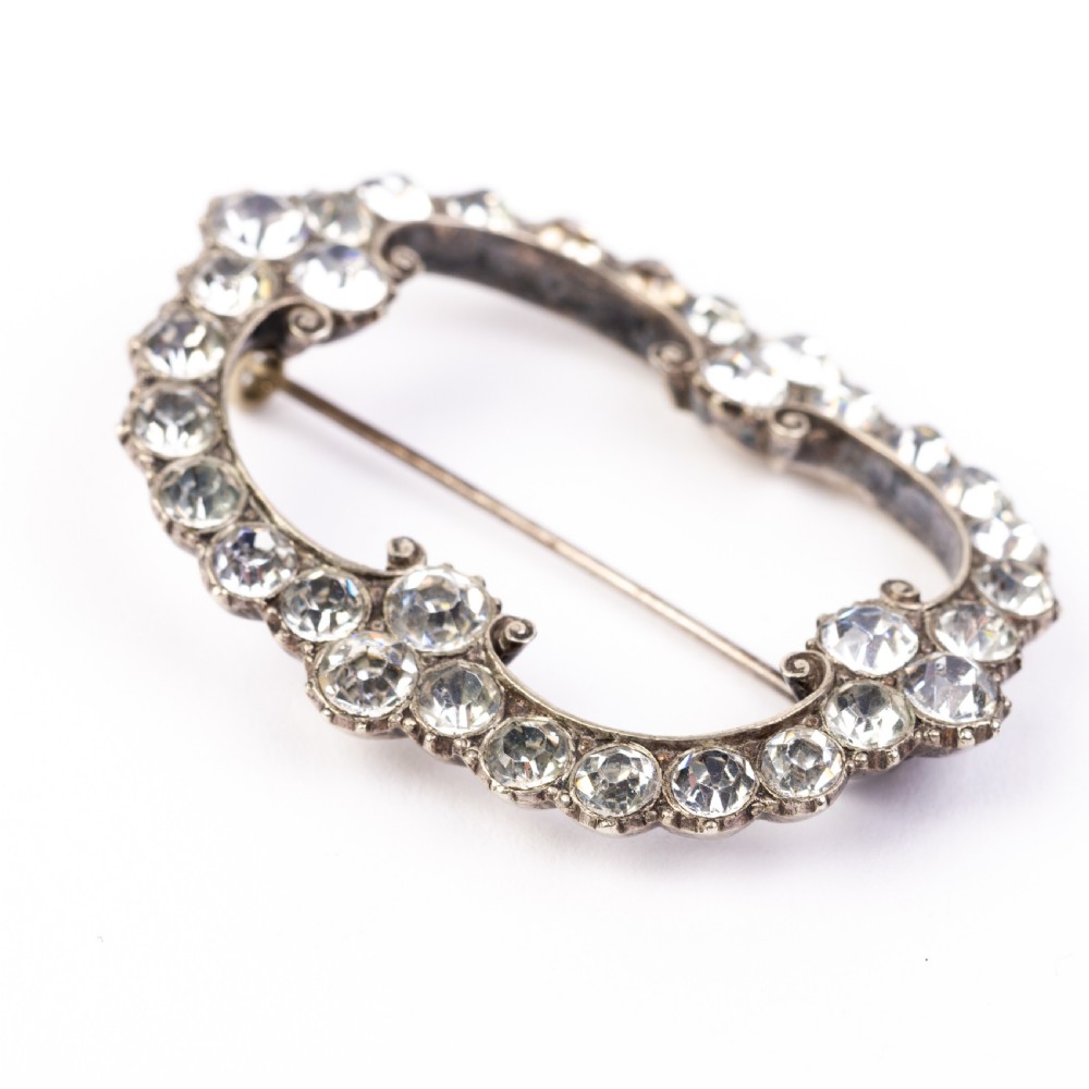 A nineteenth-century Victorian openwork oval buckle brooch set with faceted clear paste glass stones in a silver setting. View III