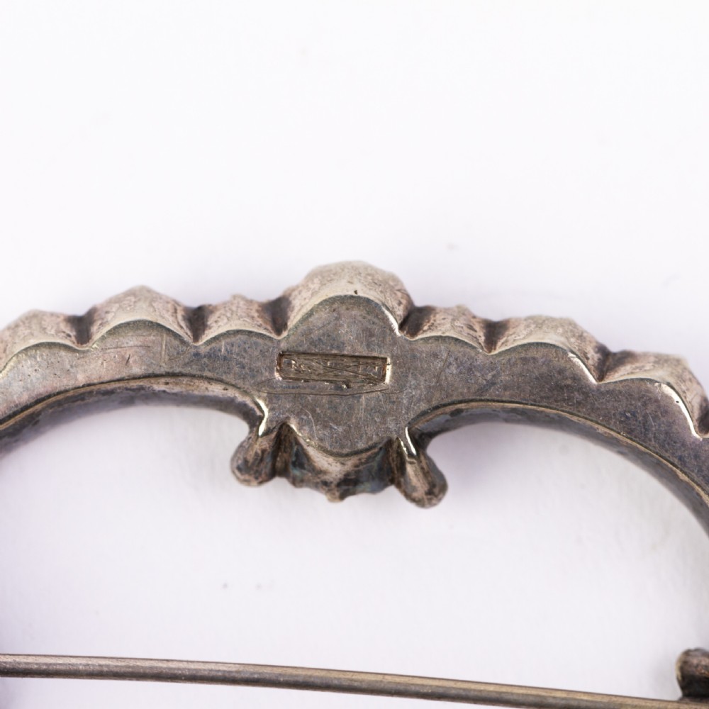 A nineteenth-century Victorian openwork oval buckle brooch set with faceted clear paste glass stones in a silver setting. View IV