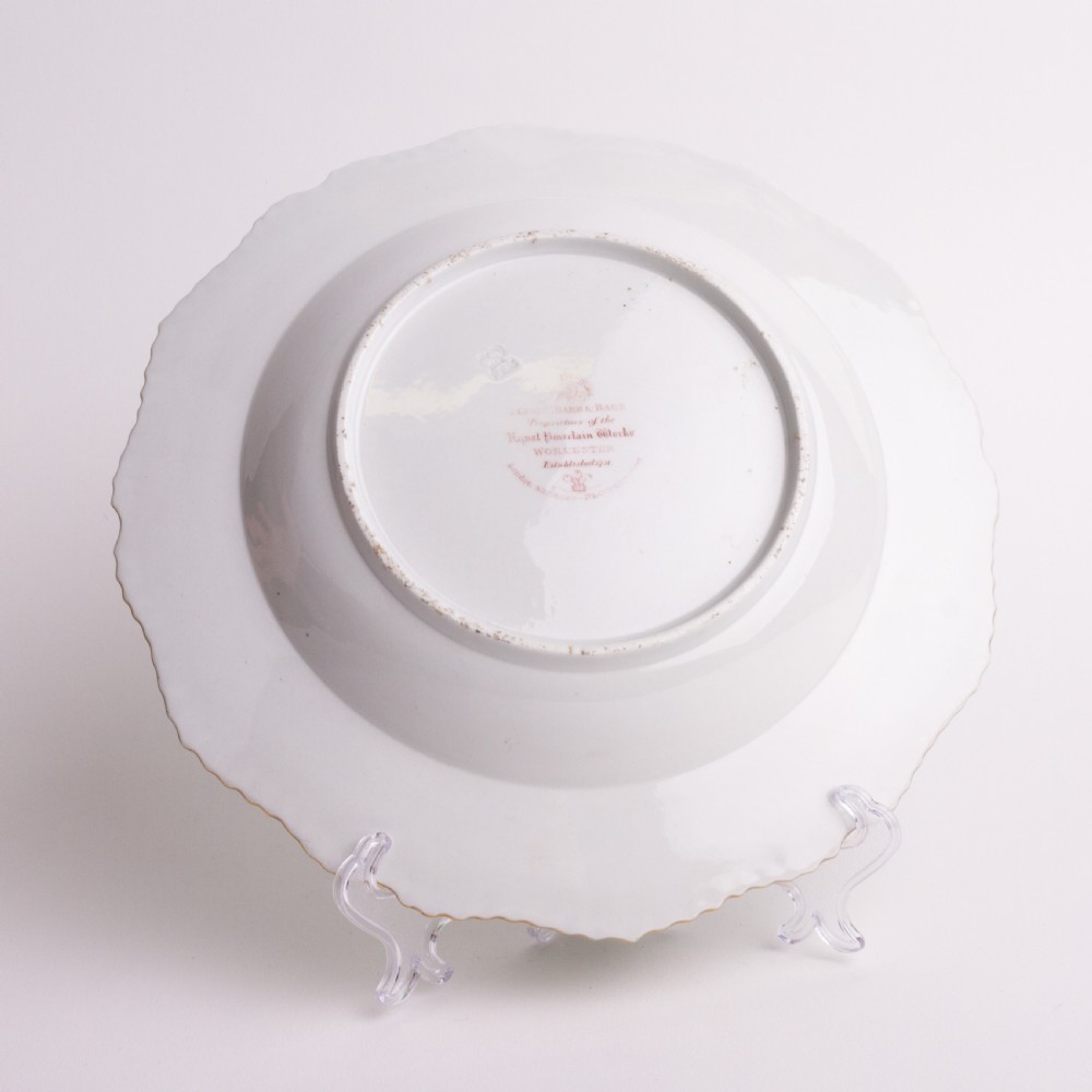A Regency period Flight Barr and Barr porcelain plate featuring a green border, a gadrooned gilt rim, and a central hand-painted crest with three swords and a serpent. View III
