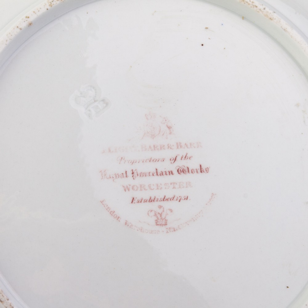 A Regency period Flight Barr and Barr porcelain plate featuring a green border, a gadrooned gilt rim, and a central hand-painted crest with three swords and a serpent. View II