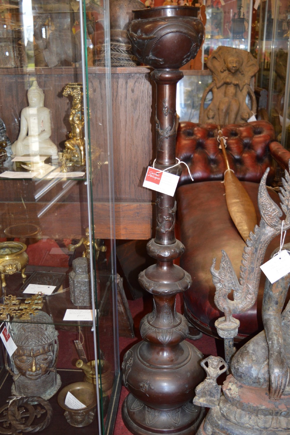 A tall 19th-century Chinese cast bronze sectional jardiniere stand featuring relief carvings of dragons and floral patterns on a tiered bulbous base.