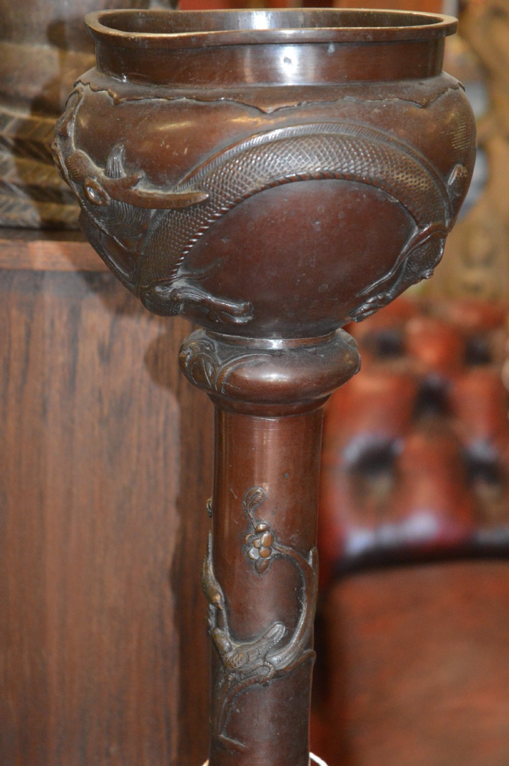 A tall 19th-century Chinese cast bronze sectional jardiniere stand featuring relief carvings of dragons and floral patterns on a tiered bulbous base. View II