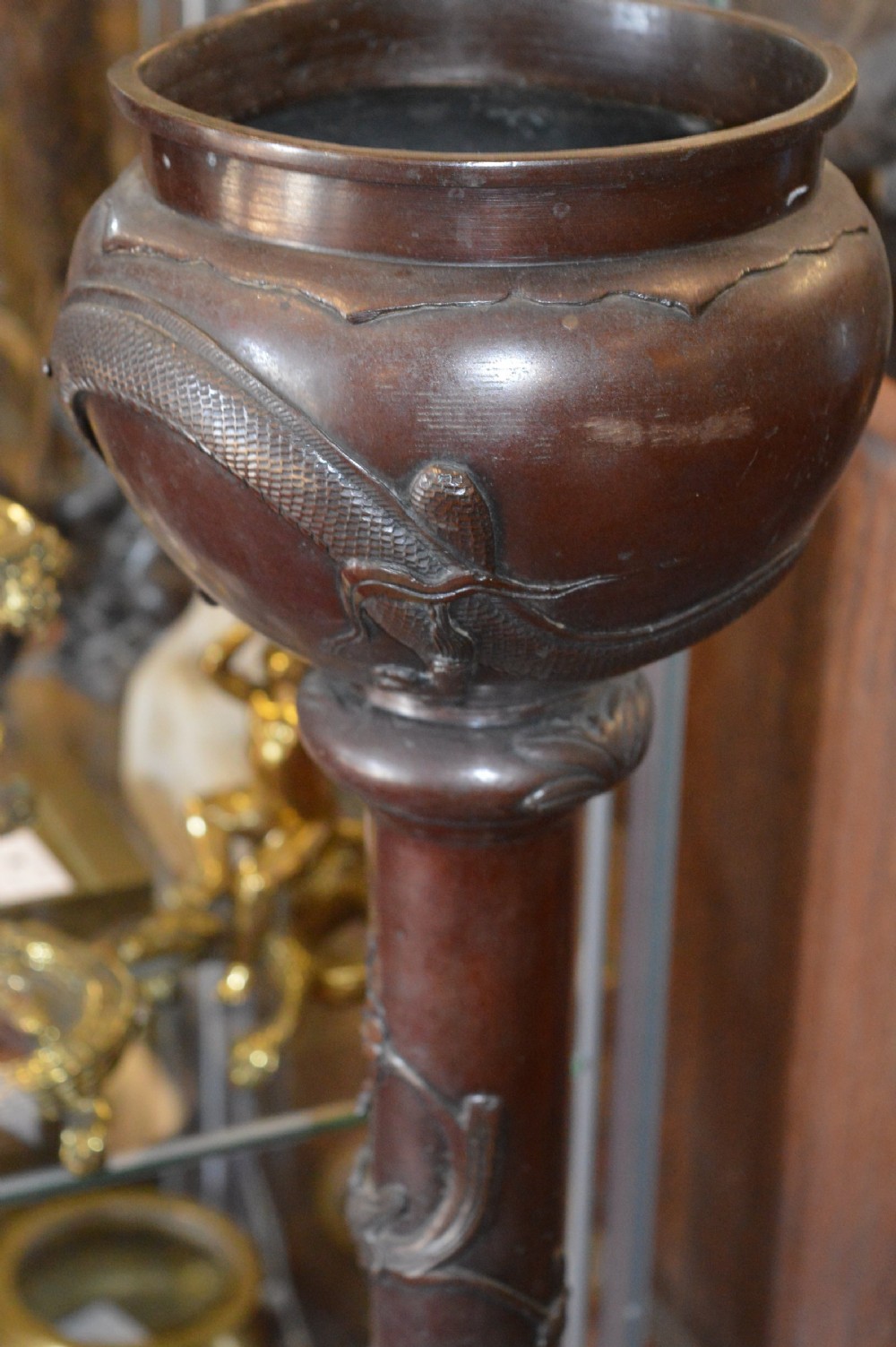 A tall 19th-century Chinese cast bronze sectional jardiniere stand featuring relief carvings of dragons and floral patterns on a tiered bulbous base. View V