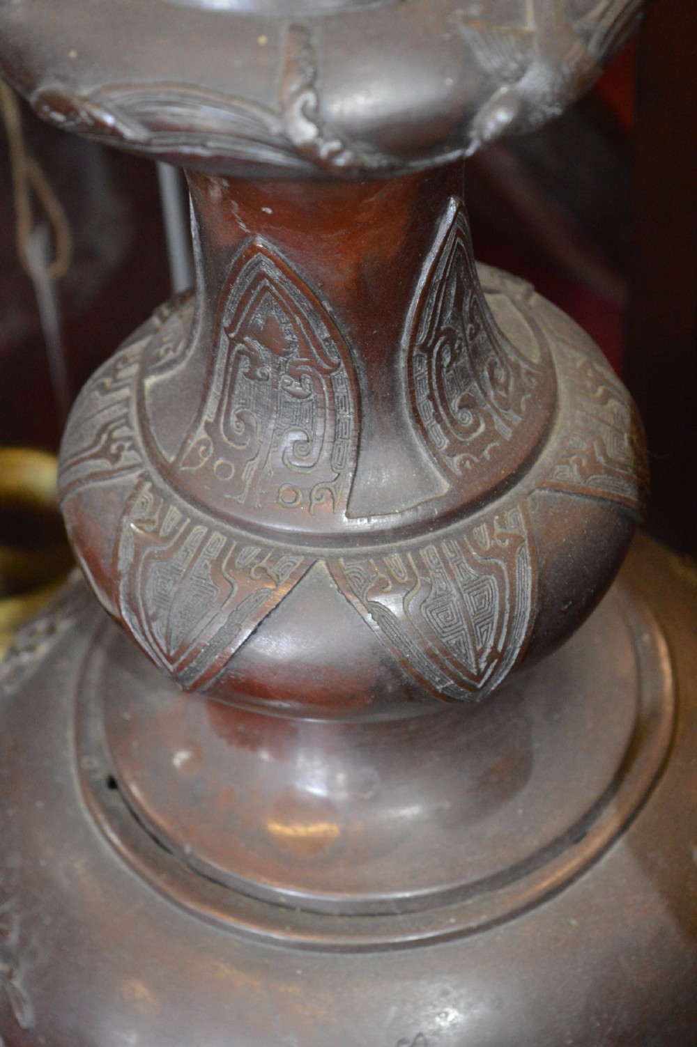 A tall 19th-century Chinese cast bronze sectional jardiniere stand featuring relief carvings of dragons and floral patterns on a tiered bulbous base. View VI