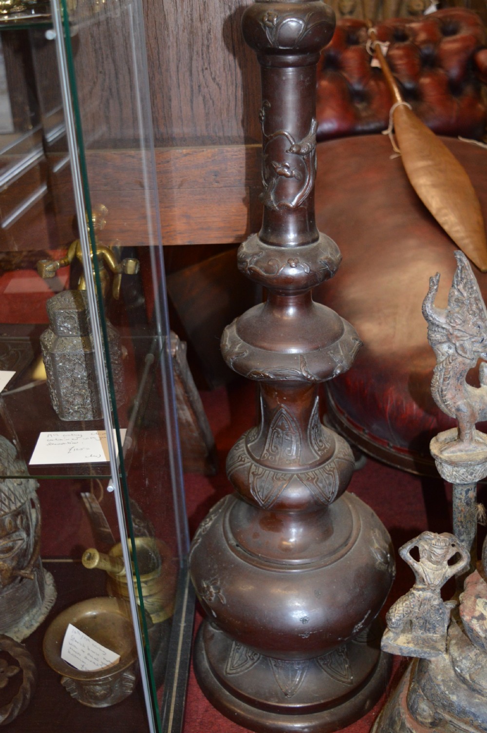 A tall 19th-century Chinese cast bronze sectional jardiniere stand featuring relief carvings of dragons and floral patterns on a tiered bulbous base. View IX