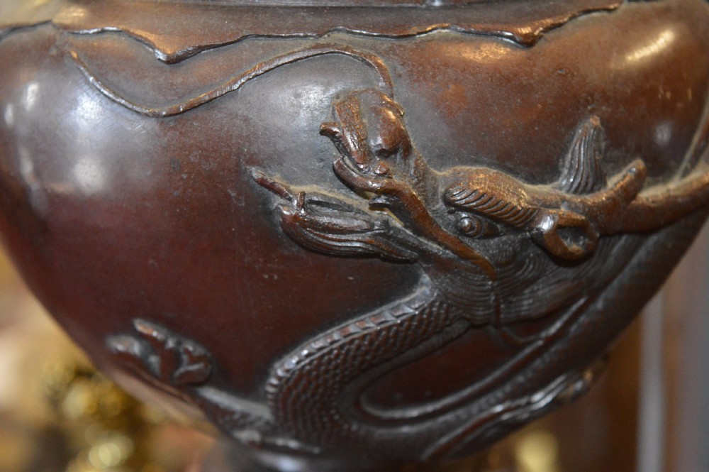 A tall 19th-century Chinese cast bronze sectional jardiniere stand featuring relief carvings of dragons and floral patterns on a tiered bulbous base. View X