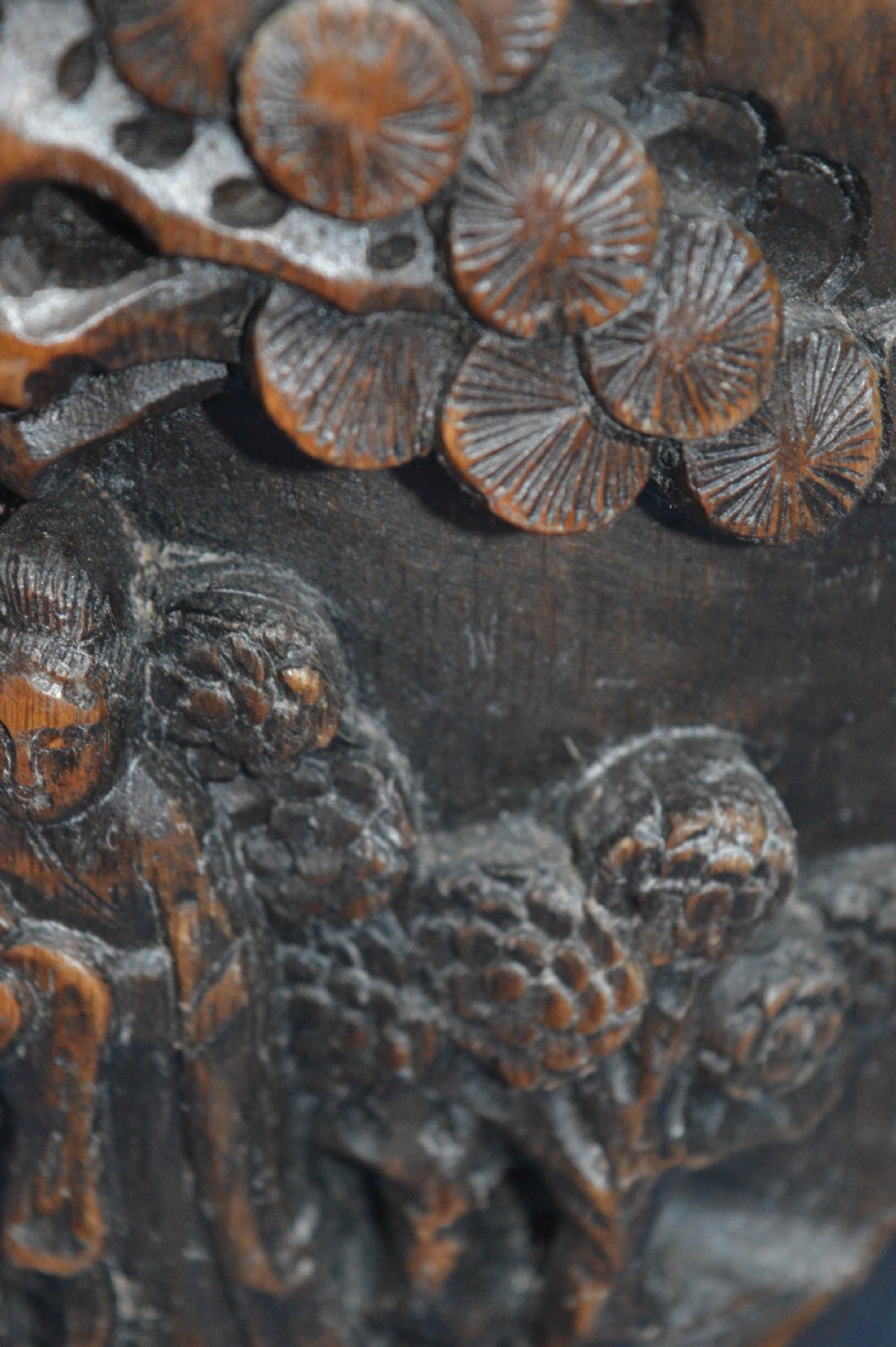A late nineteenth-century hand-carved dark brown Chinese bamboo brush pot depicting figures and pine trees in high relief. View VI