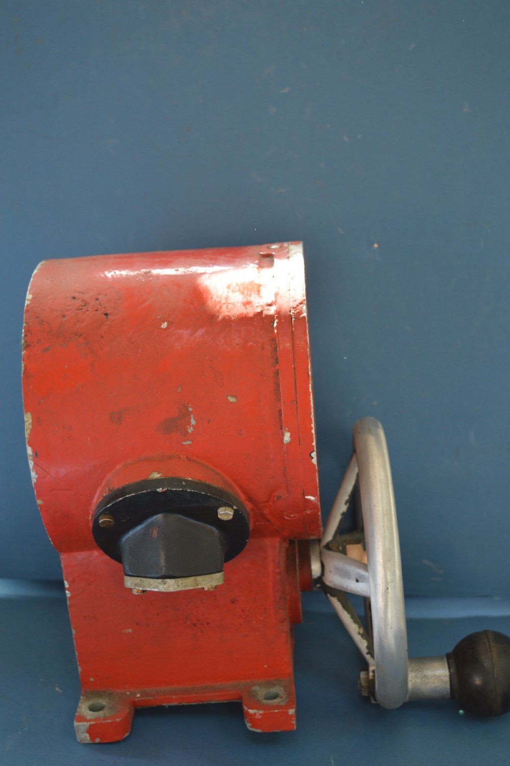 A mid-20th-century red and black painted metal ship engine order telegraph featuring a circular dial with ahead and astern markings behind glass and a four-spoke control wheel. View IV