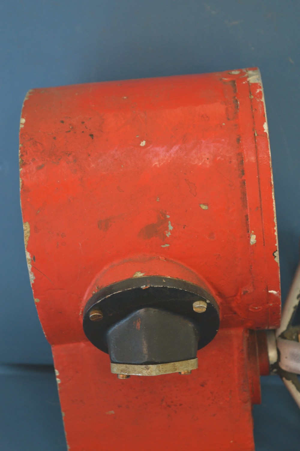 A mid-20th-century red and black painted metal ship engine order telegraph featuring a circular dial with ahead and astern markings behind glass and a four-spoke control wheel. View V