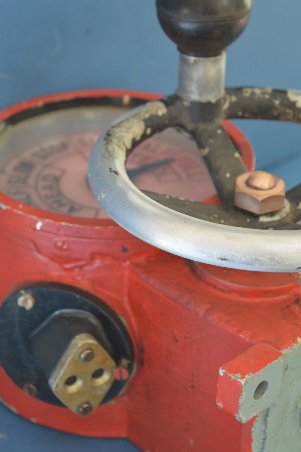 A mid-20th-century red and black painted metal ship engine order telegraph featuring a circular dial with ahead and astern markings behind glass and a four-spoke control wheel. View XI