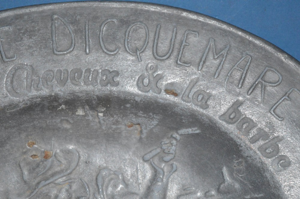 A 19th-century French pewter oval barber bowl with a crescent neck cut-out, embossed rim lettering, and a central relief scene. View III