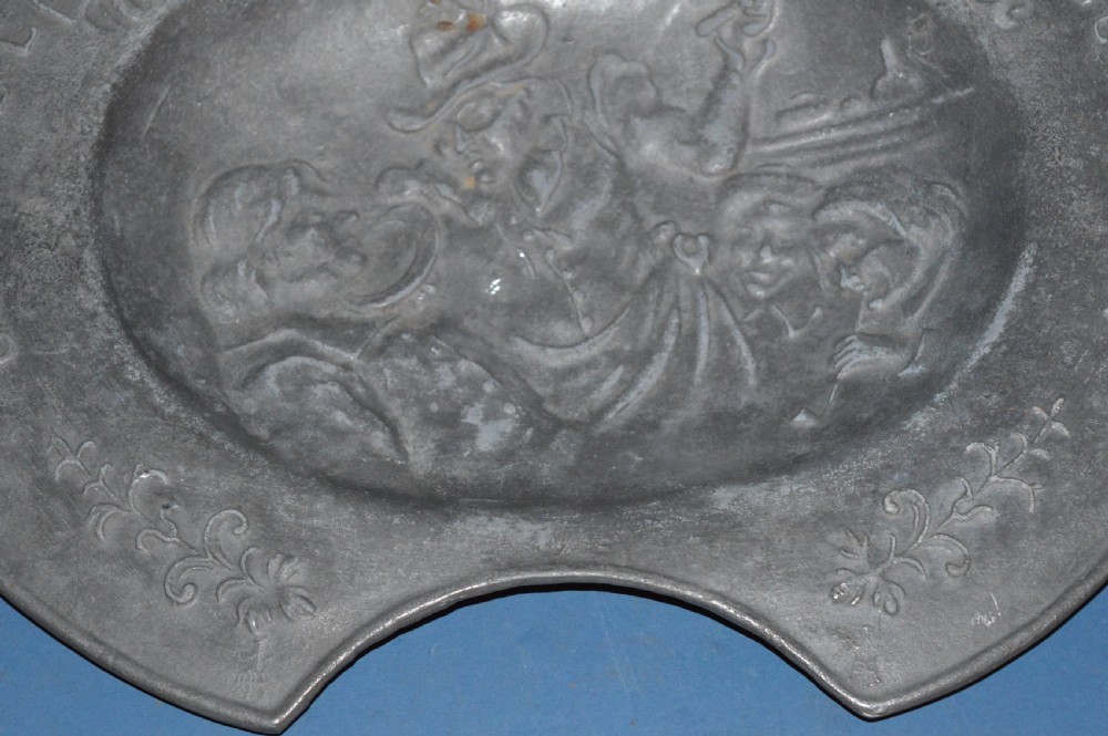 A 19th-century French pewter oval barber bowl with a crescent neck cut-out, embossed rim lettering, and a central relief scene. View VIII