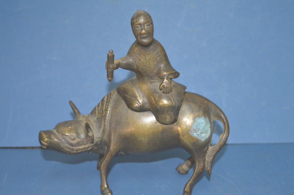 A late 19th-century cast bronze censer depicting a man dressed in robes seated astride a horned ox or water buffalo. View II