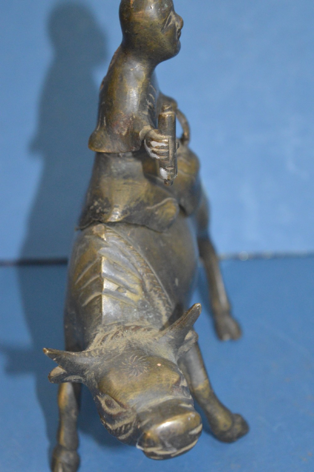 A late 19th-century cast bronze censer depicting a man dressed in robes seated astride a horned ox or water buffalo. View VI
