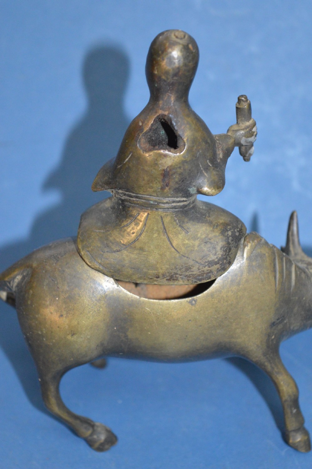 A late 19th-century cast bronze censer depicting a man dressed in robes seated astride a horned ox or water buffalo. View VII