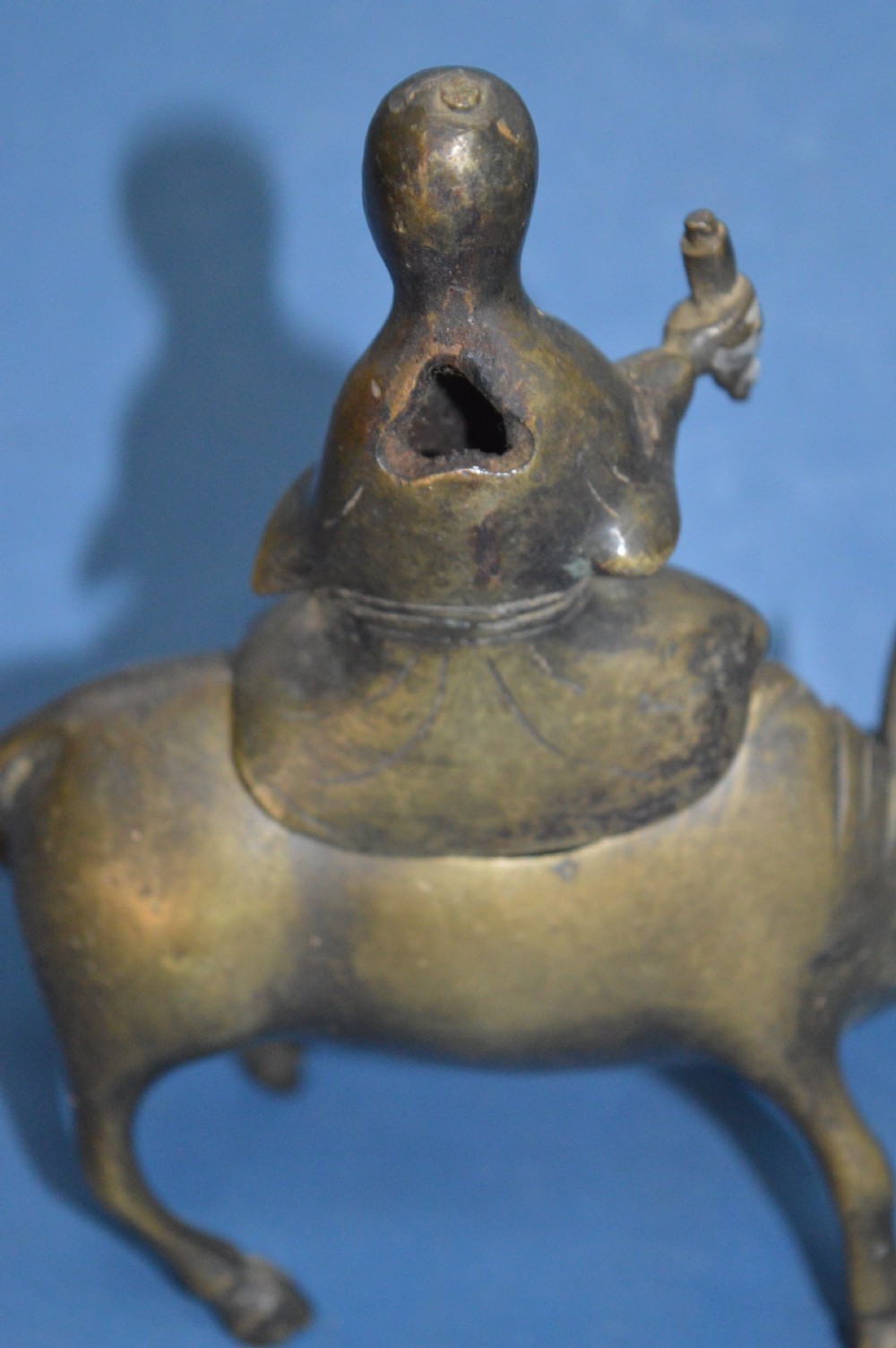 A late 19th-century cast bronze censer depicting a man dressed in robes seated astride a horned ox or water buffalo. View IX