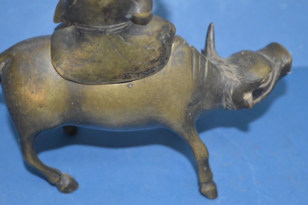 A late 19th-century cast bronze censer depicting a man dressed in robes seated astride a horned ox or water buffalo. View XI