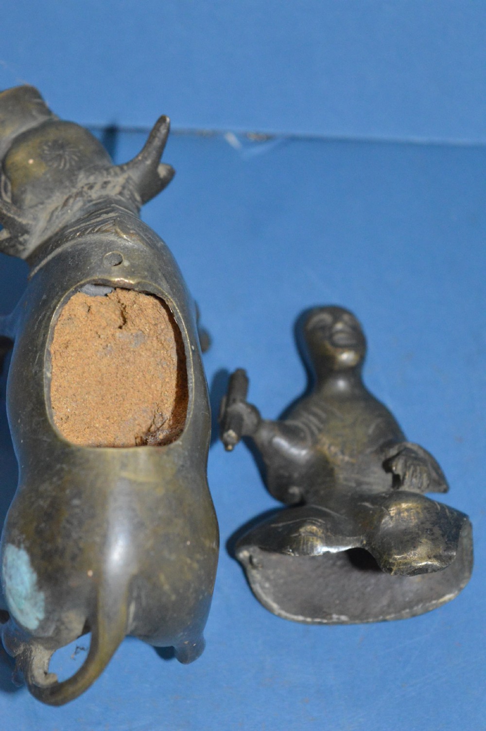 A late 19th-century cast bronze censer depicting a man dressed in robes seated astride a horned ox or water buffalo. View XII