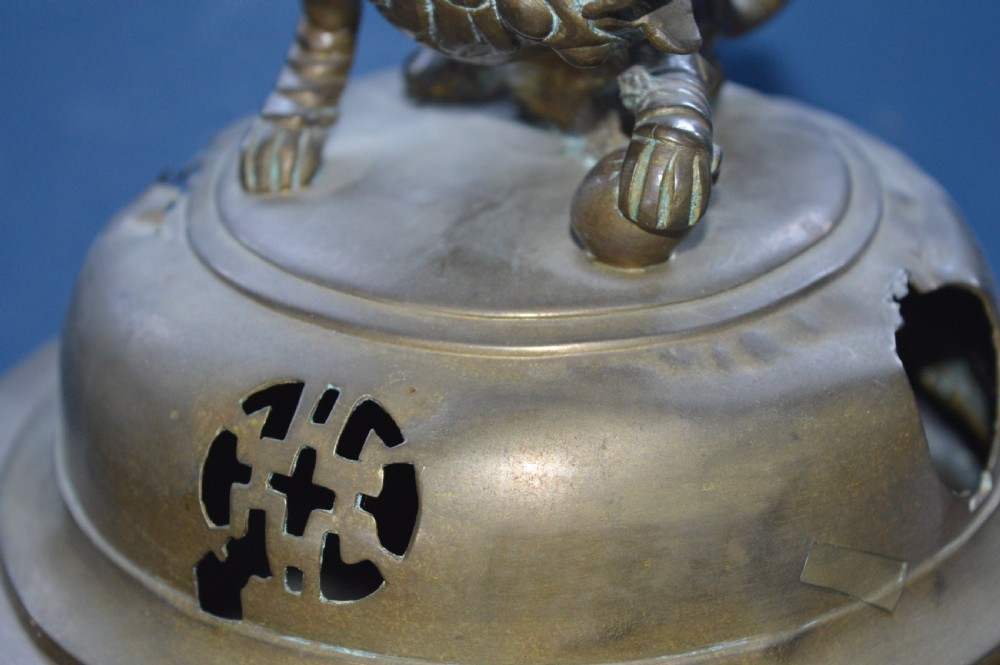A heavy Chinese bronze lidded censer featuring a foo dog lid finial, pierced cover, double beast side handles, and three tripod feet. View IV