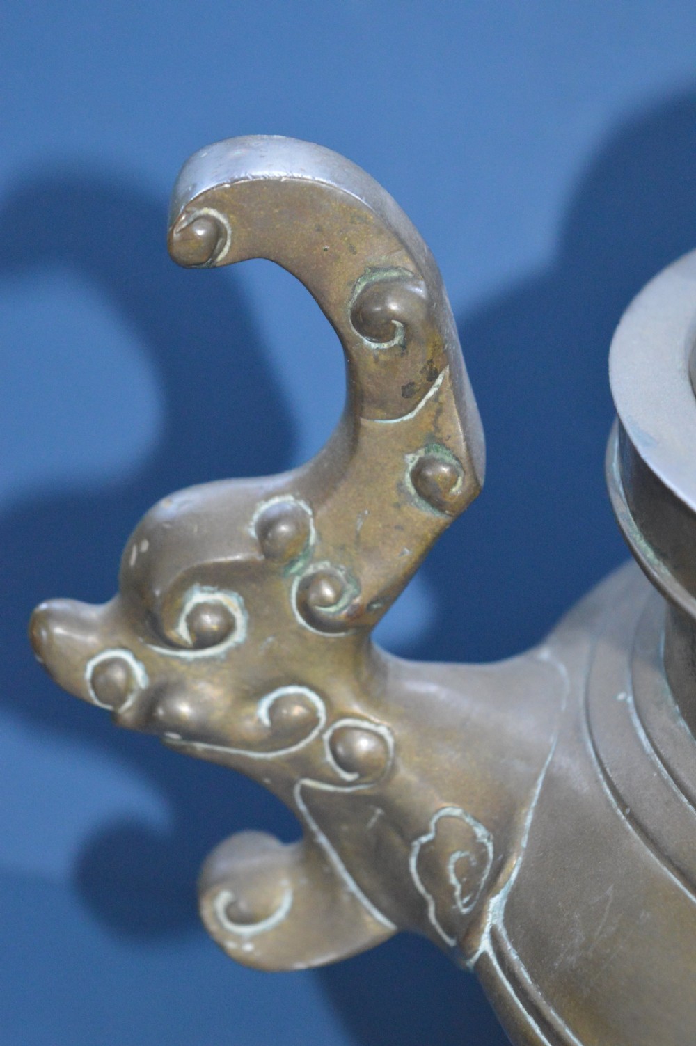 A heavy Chinese bronze lidded censer featuring a foo dog lid finial, pierced cover, double beast side handles, and three tripod feet. View V