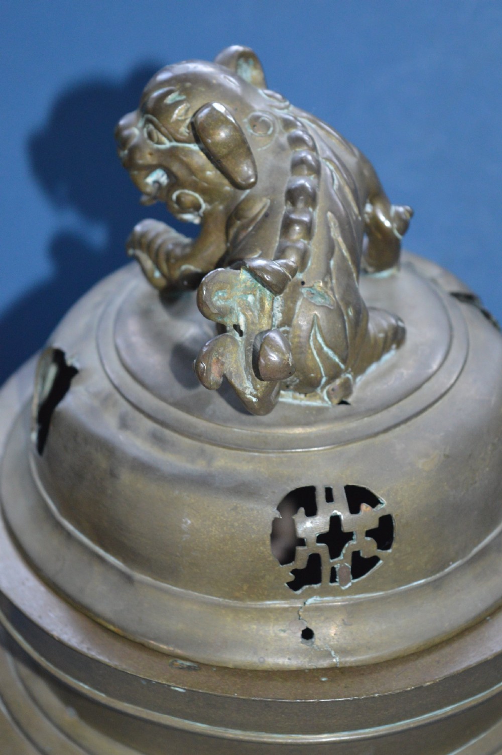 A heavy Chinese bronze lidded censer featuring a foo dog lid finial, pierced cover, double beast side handles, and three tripod feet. View VI