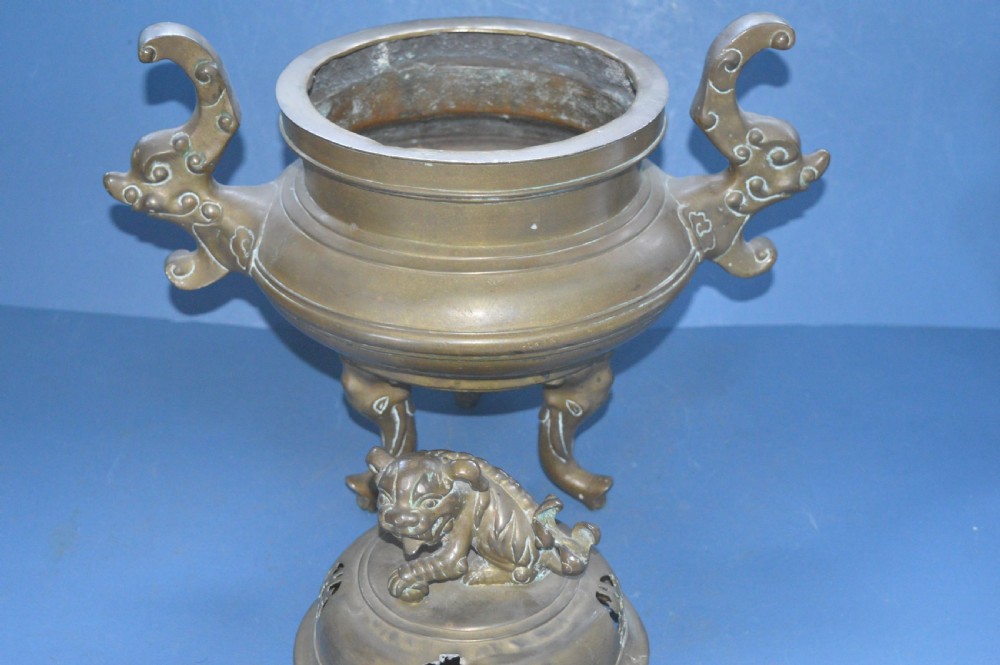 A heavy Chinese bronze lidded censer featuring a foo dog lid finial, pierced cover, double beast side handles, and three tripod feet. View VIII