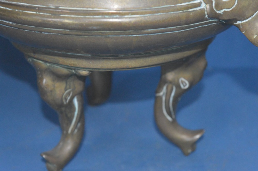 A heavy Chinese bronze lidded censer featuring a foo dog lid finial, pierced cover, double beast side handles, and three tripod feet. View IX