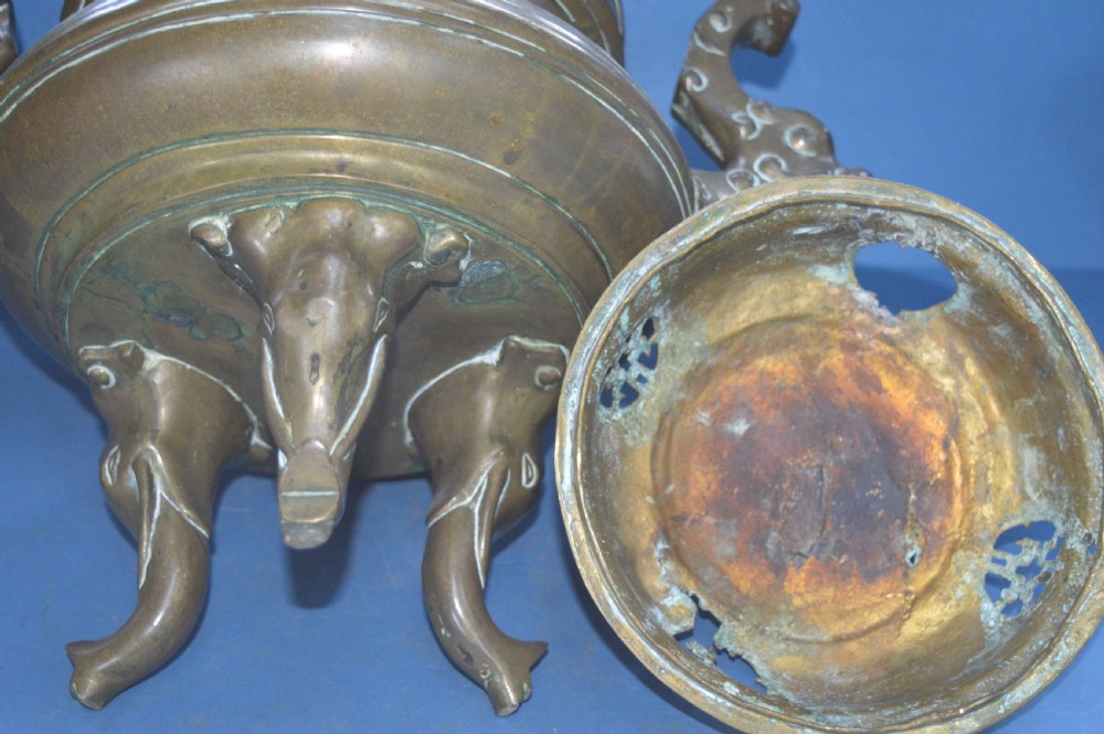 A heavy Chinese bronze lidded censer featuring a foo dog lid finial, pierced cover, double beast side handles, and three tripod feet. View XI
